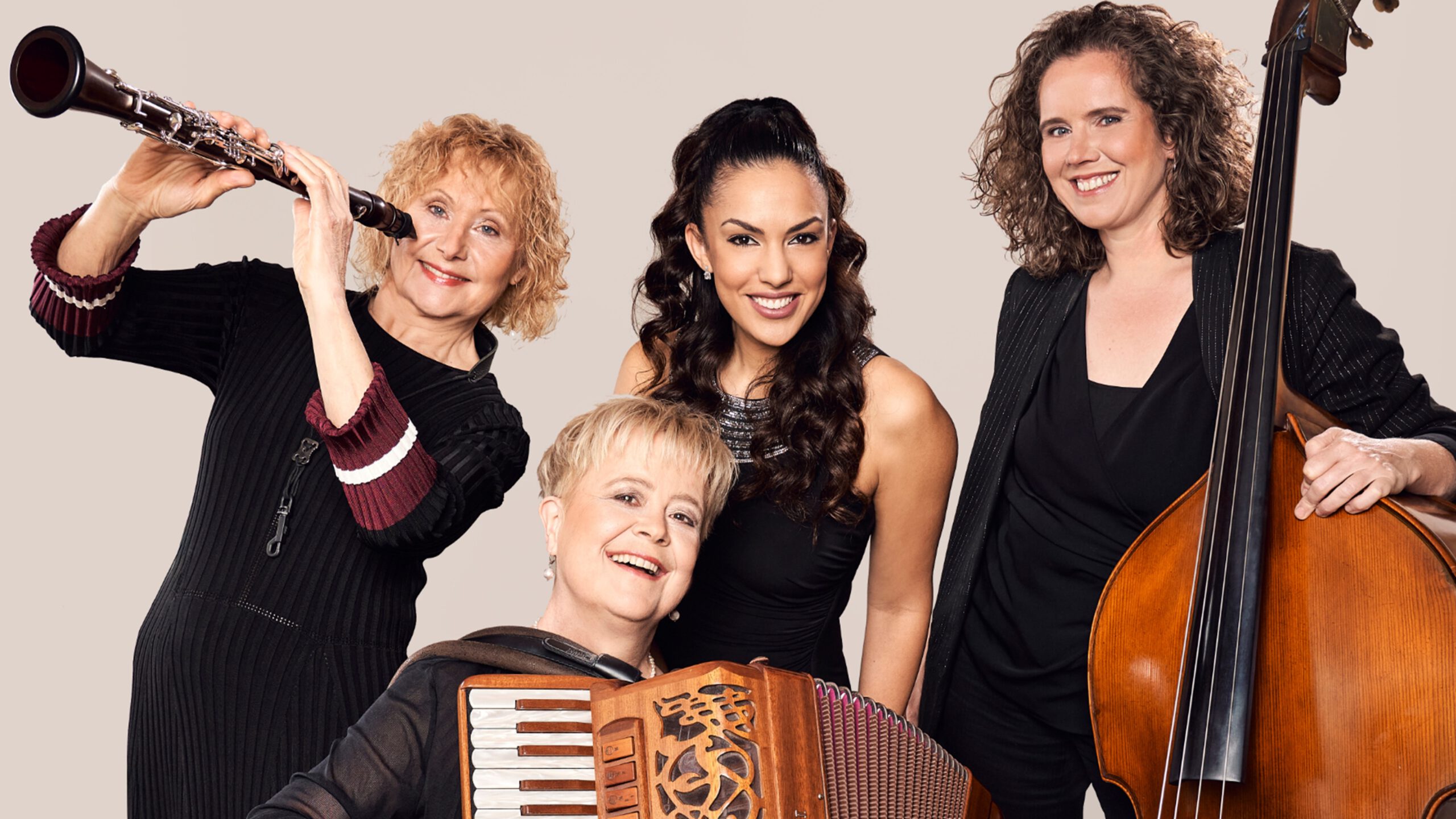 Vier lächelnde Musikerinnen von Klezmers-Techter mit Klarinette, Akkordeon, Kontrabass, schwarz gekleidet vor hellem Hintergrund.